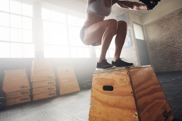 Woman box jumping at a crossfit gym