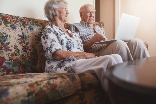 Elderly couple on sofa using laptop