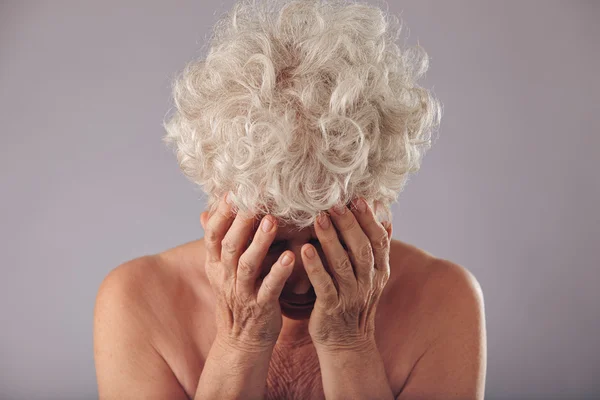 Sad senior woman on grey background