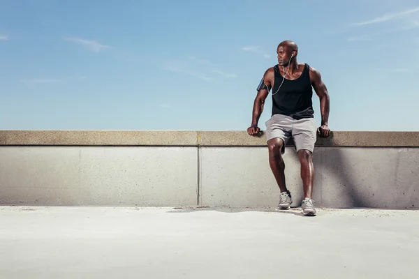 Male runner relaxing on embankment looking away copyspace