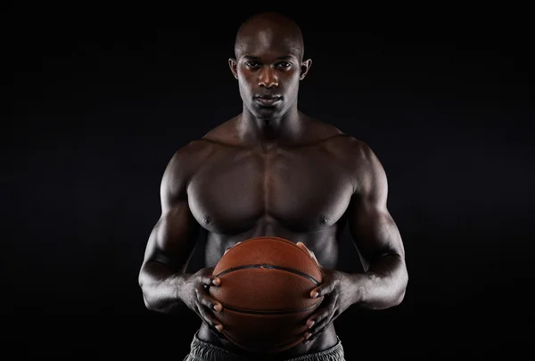 Muscular young man shirtless holding a basketball