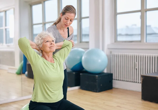 Trainer helping senior woman exercising