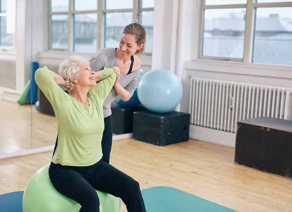 Happy senior woman exercising with female instructor