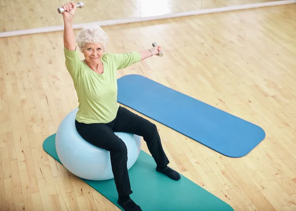 Active senior woman at gym exercising with weights