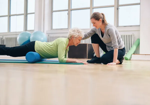 Physical therapist helping elderly woman in her workout