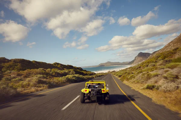 Couple driving in small beach buggy car on open road