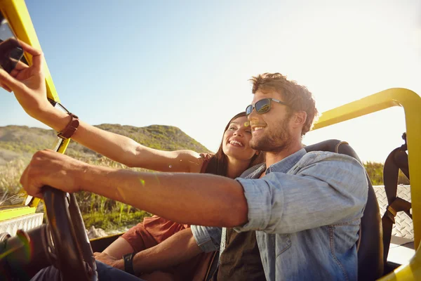 Woman taking selfie on road trip with man