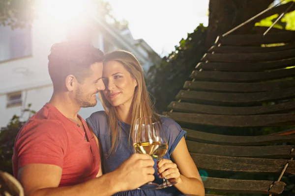 Romantic young couple in hammock toasting wine