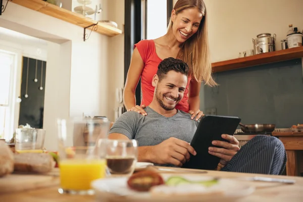 Happy young couple in kitchen using tablet pc