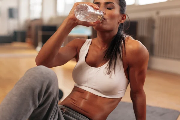 Fitness woman drinking water from bottle at gym