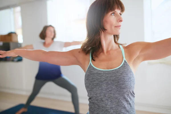 Fitness trainer doing the warrior pose at yoga class