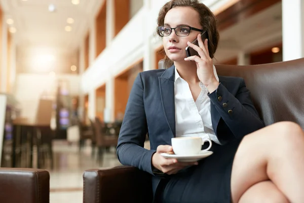 Businesswoman sitting at coffee shop using mobile phone