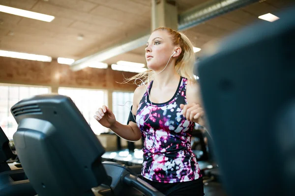 Young female running on treadmill in health club