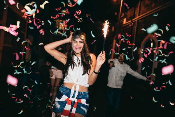 Friends partying outdoors with confetti and sparklers