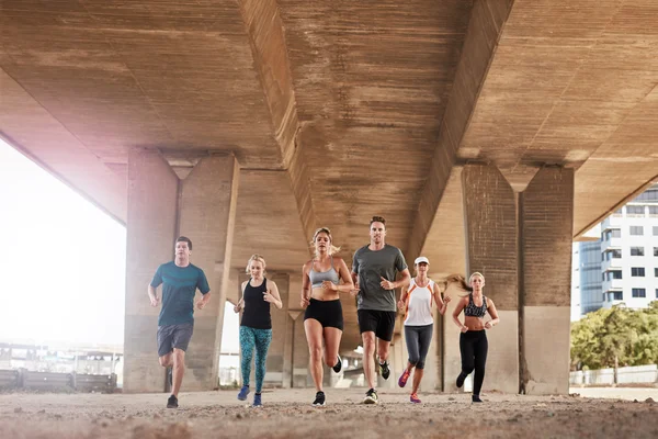 Group of healthy people running under a bridge