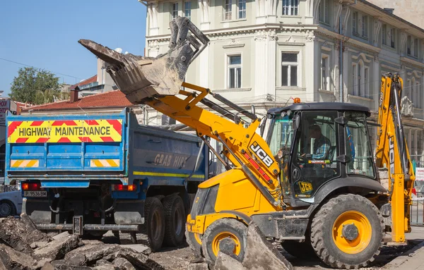 Road works. Yellow tractor removes old asphalt