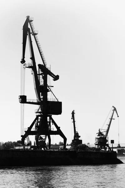 Dark silhouettes of industrial port cranes. Danube River
