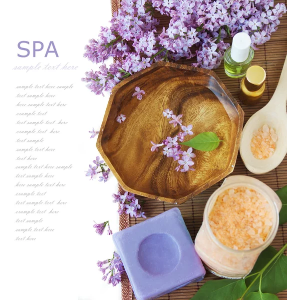 Lilac spa (fresh lilac flowers,spa salt, zen stones, Herbal massage balls, towel) on a wooden bord (with easy removable text)