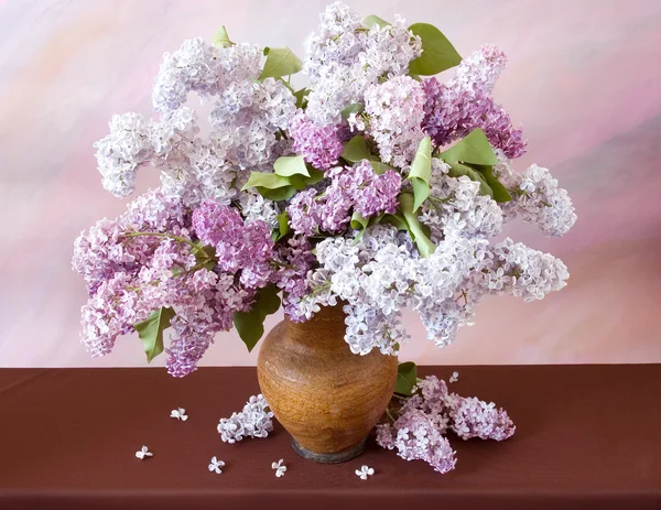 Still life with huge bunch of lilac and lily of the valley flowers on painting background