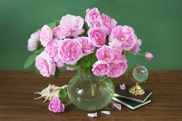 Still life with huge bunch of pink roses, books and globe on painting background
