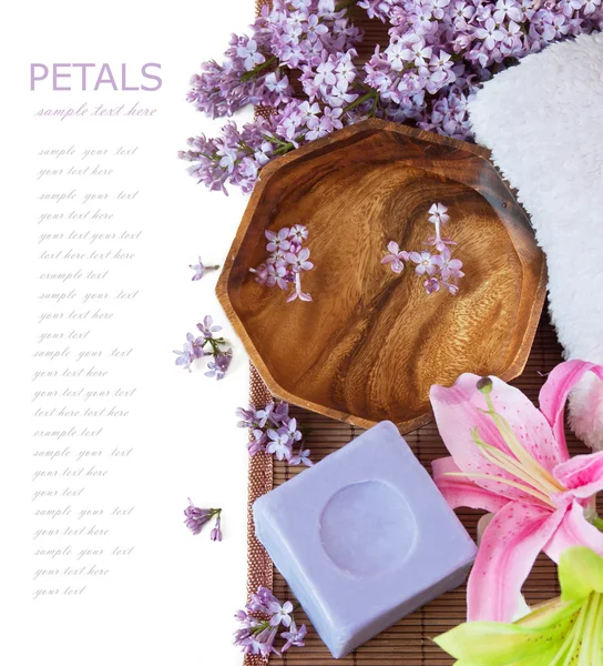 Lilac spa (fresh lilac flowers,spa salt, zen stones, Herbal massage balls, towel) on a wooden bord (with easy removable text)