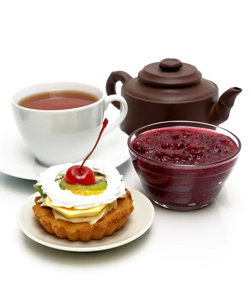 Cake with fruit, cranberry jam, a cup of tea and a clay pot on a