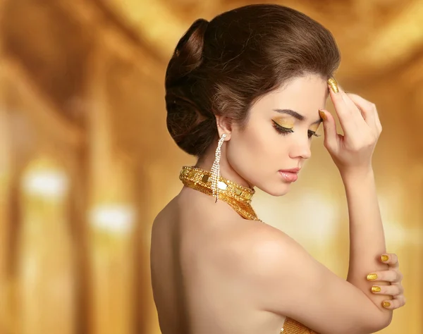 Makeup. Beautiful fashion woman in gold, elegant lady in expensi