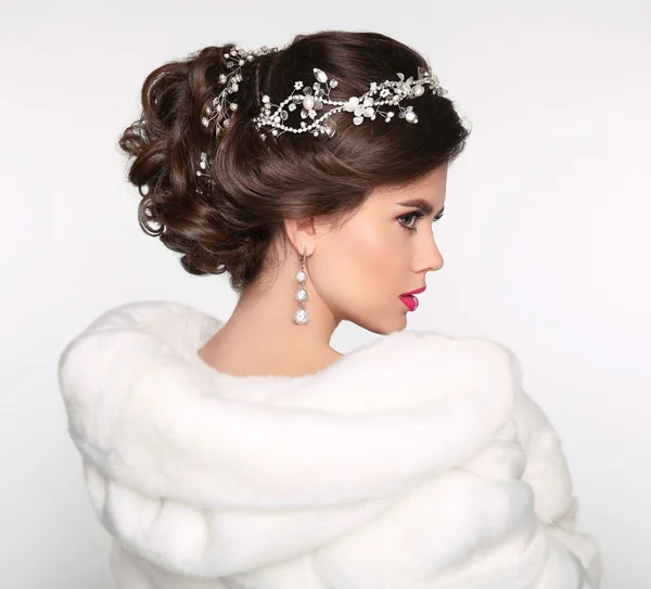 Elegant brunette woman in white fur coat. Wedding Hairstyle. Bea