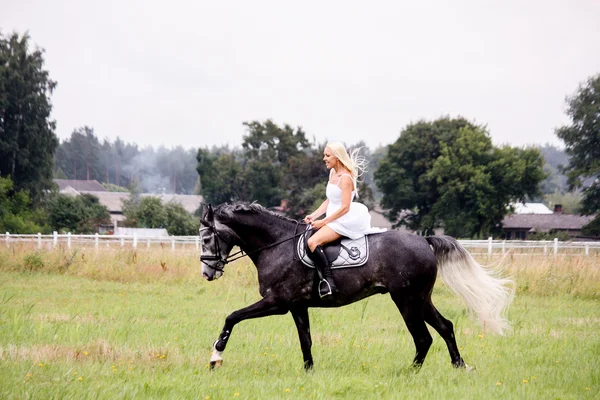 Beautiful blonde woman and gray horse riding