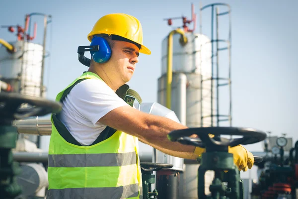 Engineer in worker\'s gear inspecting a valve