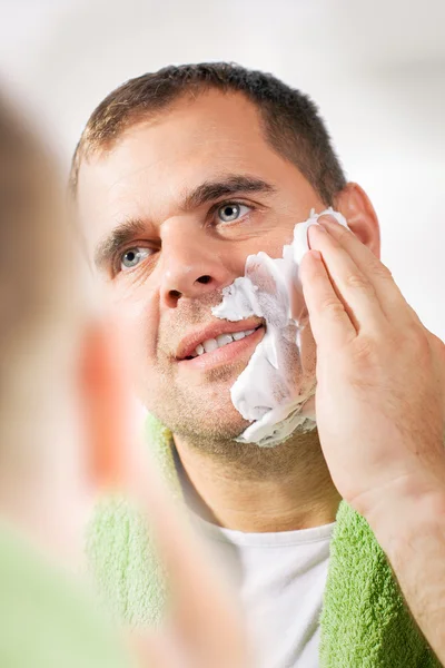 Handsome young man is shaving his face
