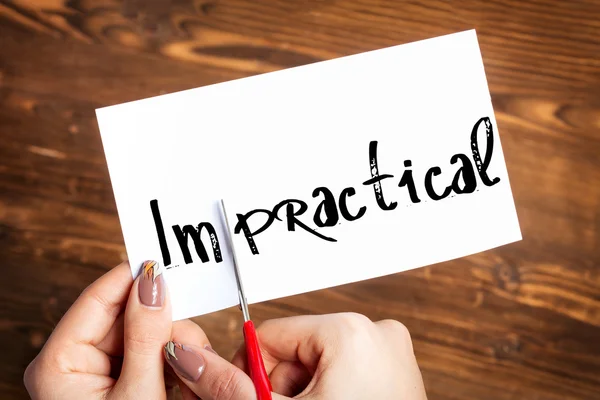 Woman hands cutting card with the word impractical