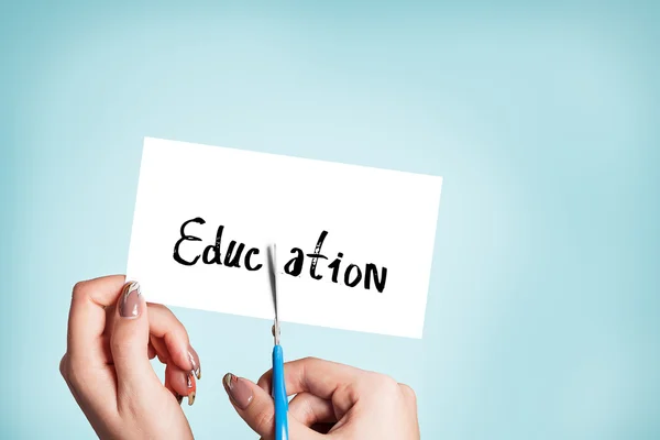 Woman hands cutting card with the word education