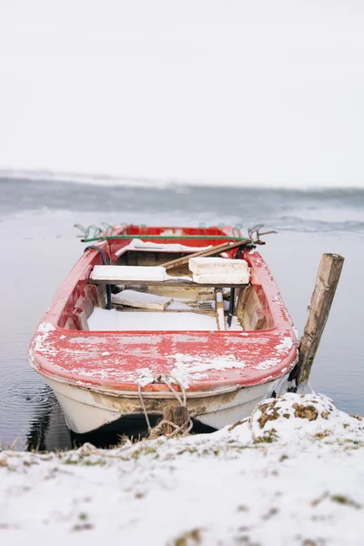 The boat in the winter on the freezing lake