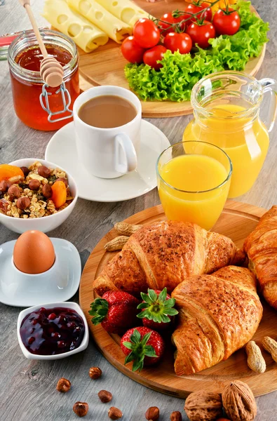 Breakfast consisting of croissants, coffee, fruits, orange juice