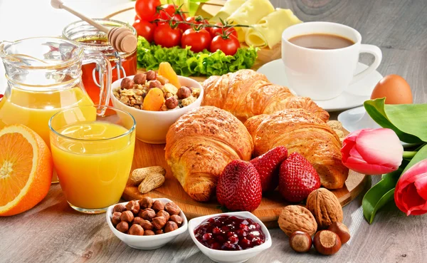 Breakfast consisting of croissants, coffee, fruits, orange juice