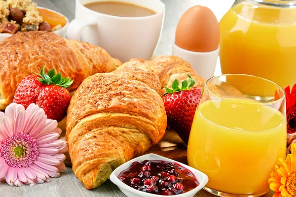 Breakfast consisting of croissants, coffee, fruits, orange juice