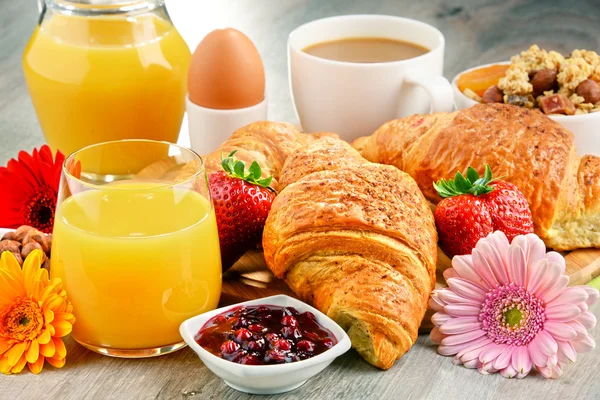 Breakfast consisting of croissants, coffee, fruits, orange juice