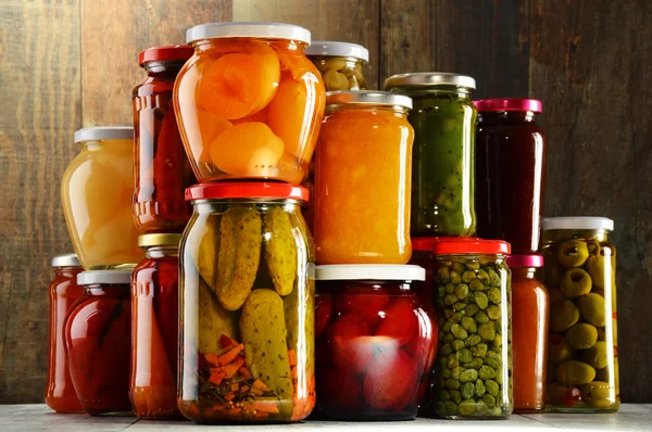 Jars with pickled vegetables, fruity compotes and jams isolated