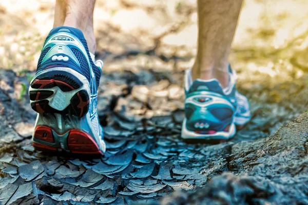 Runner feet running on crack road closeup on shoes. Man fitness