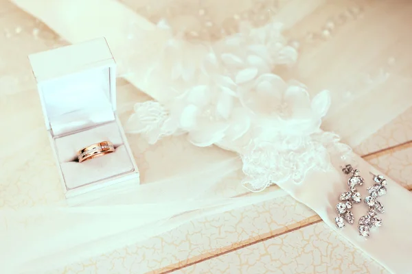 Engagement ring in white wedding box with bride ear-rings on vei