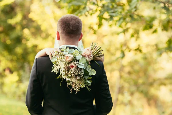 Bride hug groom with rustic bouquet on wedding ceremony in fores