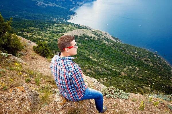 Tourist sits on top of the mountain and enjoy the view of the se
