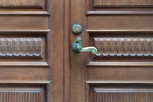 The door is made of carved wood with a vintage a handle
