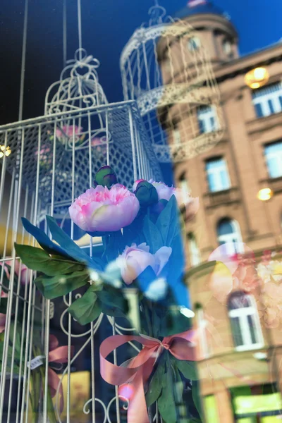 Bird cage and a bouquet of flowers in the window of the house wi