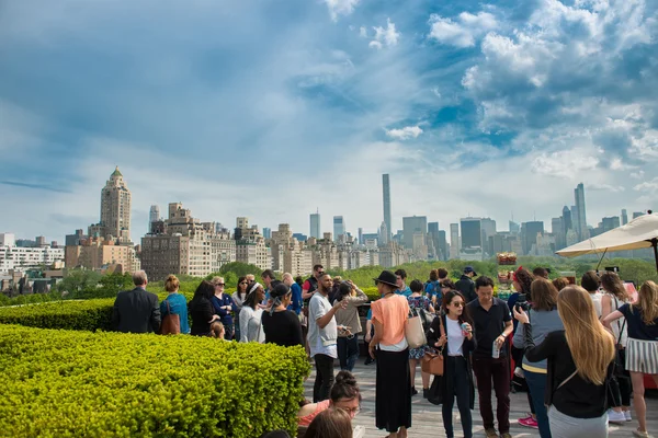 New York City - May 14, 2016: People chilling on rooftop party with Manhattan and Central Park view of the Metropolitan Museum of Art in New York.