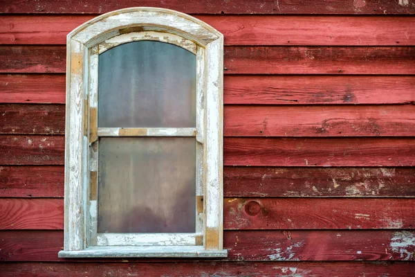 Old widow frame with dirty glass on red wooden house wall