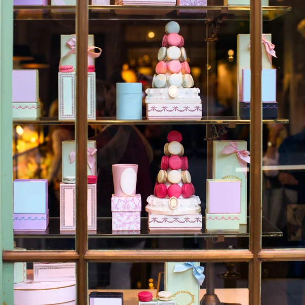 Beautiful colourful tasty macaroons cakes sweets and presents in the boxes display in window at the street shop