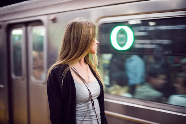 Beautiful woman stand at subway station looking at arriving metro train
