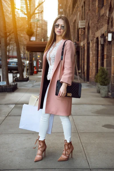 Fashionable model woman posing with shopping bags on city street